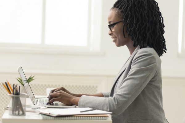 African American Lady Using Laptop In Office, Side View, Panorama